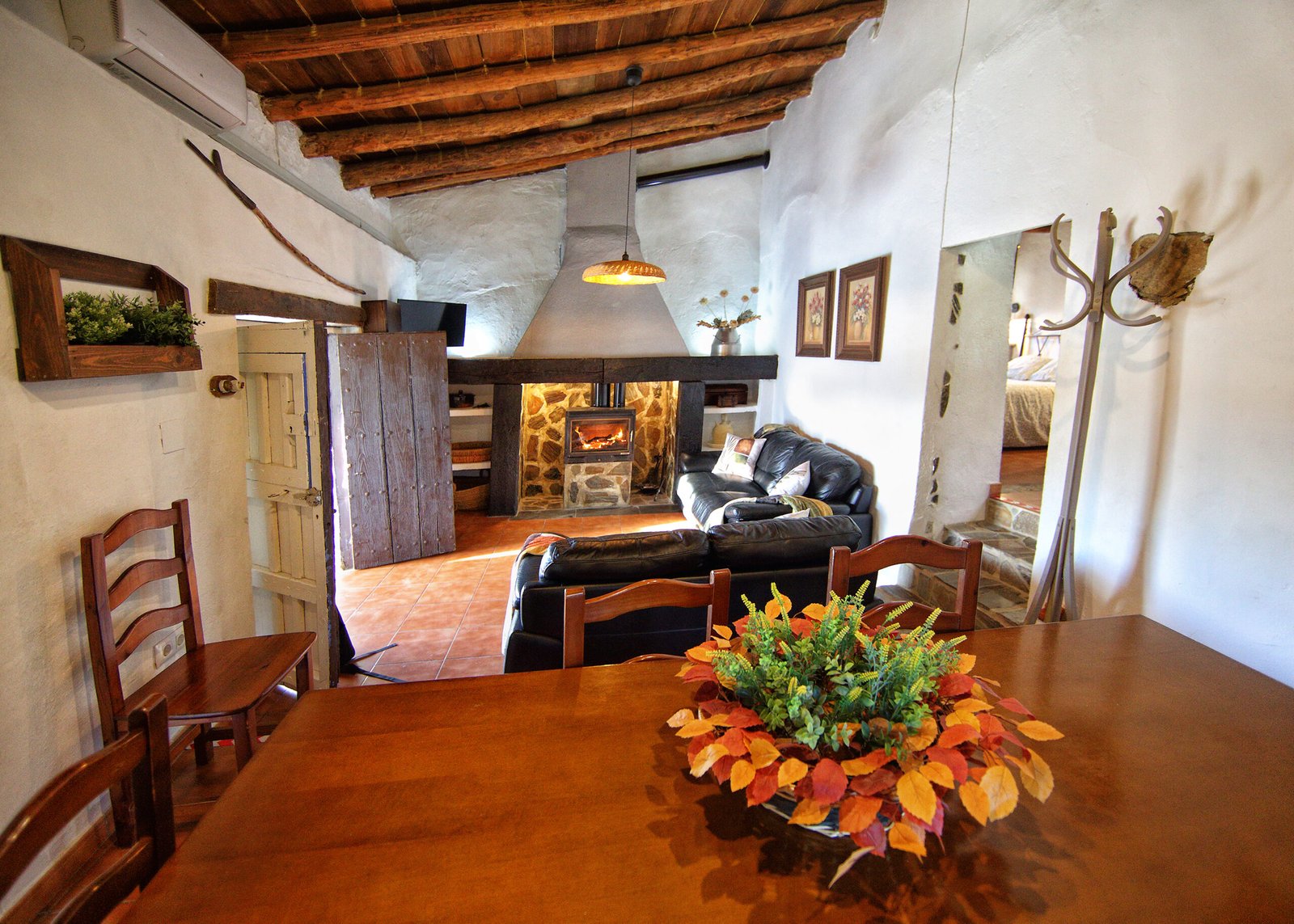 Salón acogedor con chimenea y decoración tradicional Salón rústico con chimenea de leña y techos de madera en casa rural