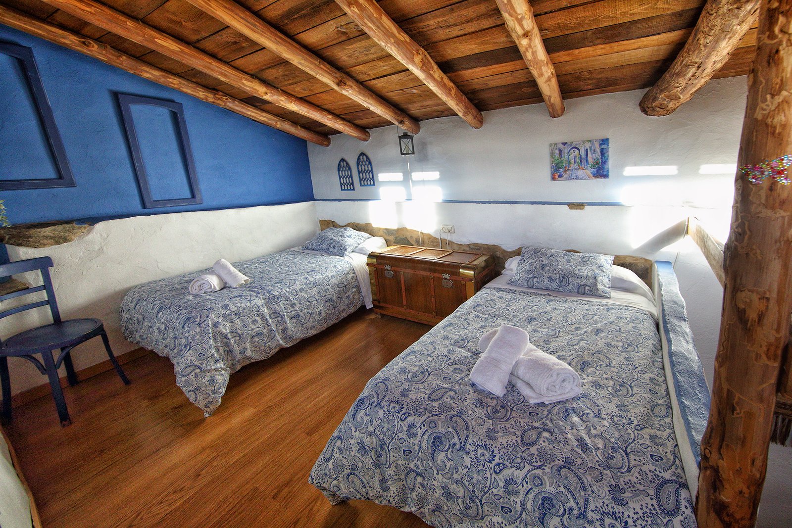 Habitación abuhardillada con techo de madera, una cama de matrimonio y dos camas individuales en Mirador de Santa Ana.