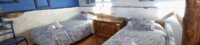 Habitación abuhardillada con techo de madera, una cama de matrimonio y dos camas individuales en Mirador de Santa Ana.
